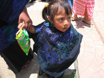 Mayan toddler holding an open Cheetos bag