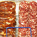 Vacuum-sealed, sliced red processed meat in a store shelf