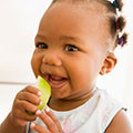 Baby smiling, holding an apple slice