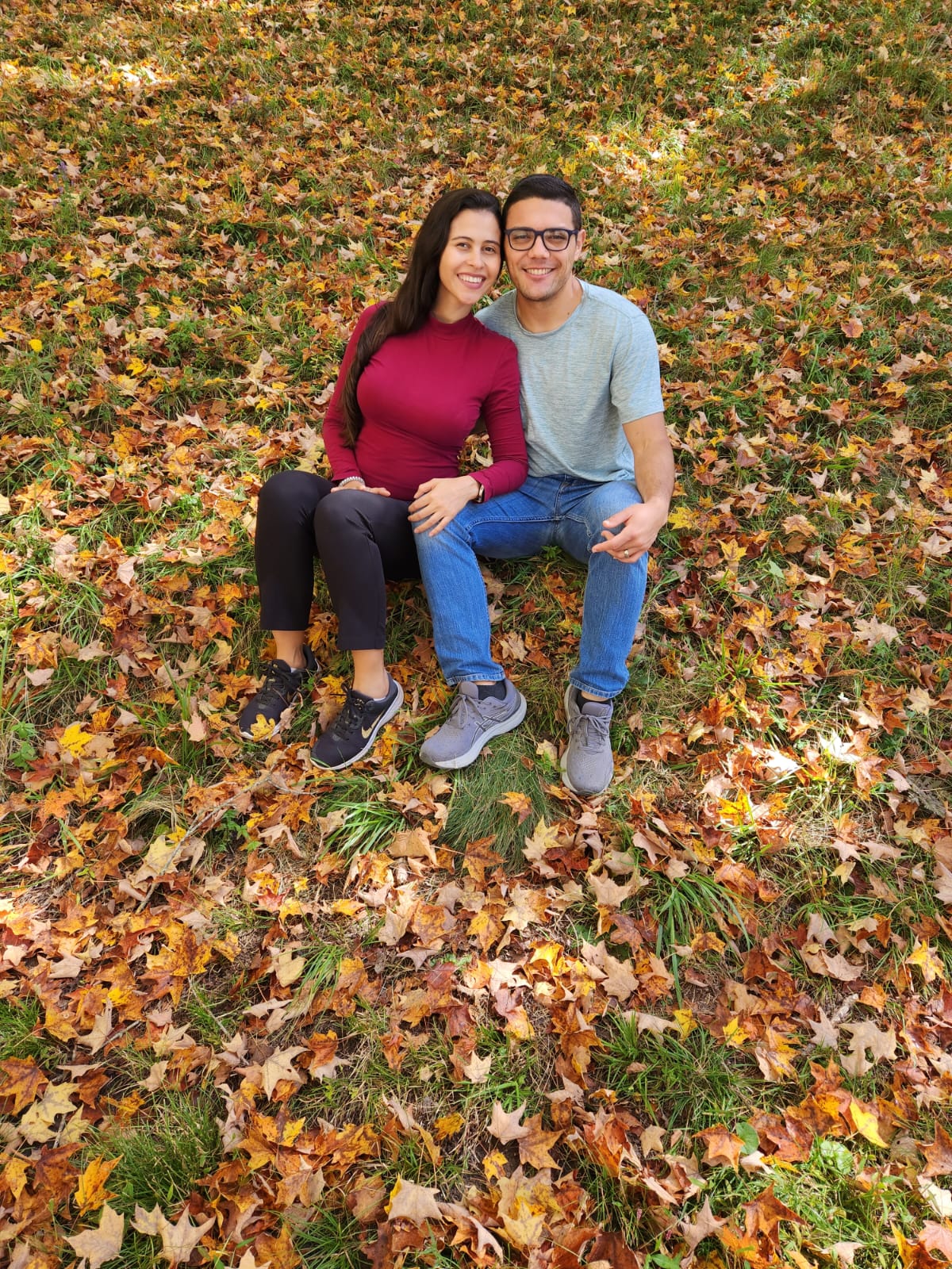 Jonathan Lara-Arévalo and wife Lorena sitting on the ground among fall leaves
