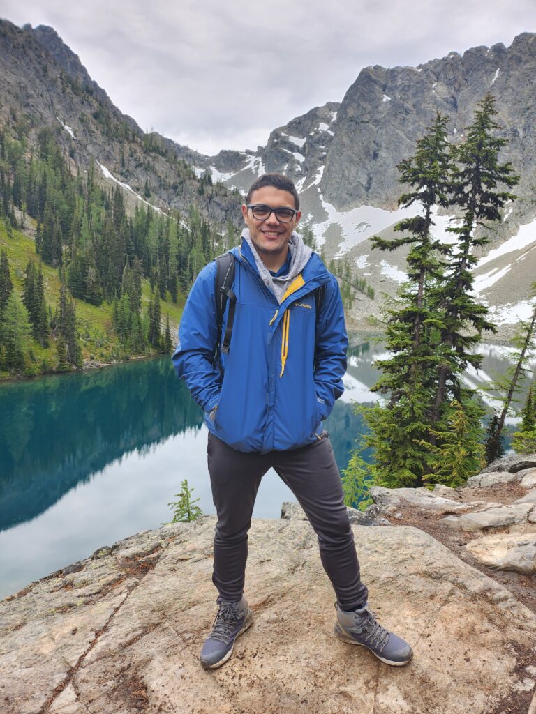 Jonathan Lara-Arévalo on a hike, posing in front of lake and mountains