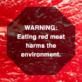 Background image of raw steak, foreground black octagonal warning label